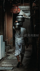 印度小巷中头顶水罐的男子背影