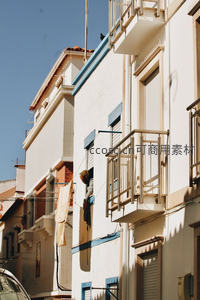 阳光下的白色公寓楼，晾衣绳随风轻扬