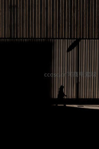 剪影行人走过现代建筑光影长廊