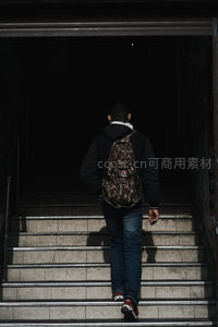 背影少年拾级而上，光影交错间走向未知