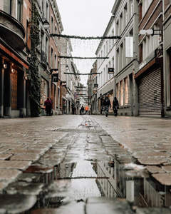 雨后石板街水洼倒映着节日装饰的店铺