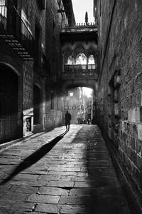 阳光穿透古巷照亮行人身影