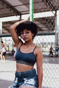 街头时尚女孩倚靠铁网，自信展现个性风采