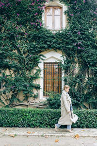 花墙前漫步的优雅女士身影