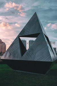 金属几何雕塑穿插城市天际线黄昏