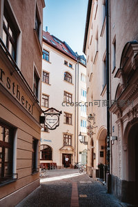 阳光洒落的欧洲窄巷，复古招牌与石板路