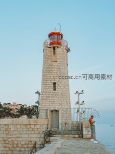 海边石砌灯塔与行人静谧时光