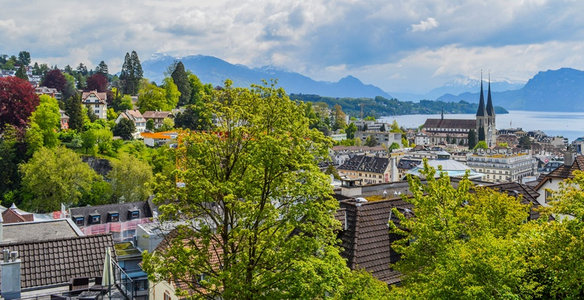 卢塞恩湖畔城市全景，绿树掩映古教堂与雪山背景