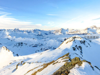航拍阿尔卑斯雪山群峰，晨光洒落雪脊，云海缭绕山谷间