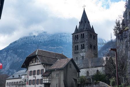 雪峰环抱下的古老教堂尖塔，传统木屋与石砌钟楼映衬冬日山村
