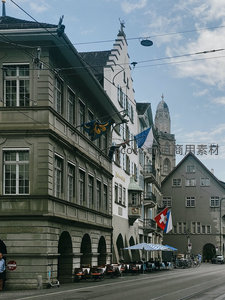 苏黎世老城街角历史建筑群，电车轨道与瑞士国旗飘扬
