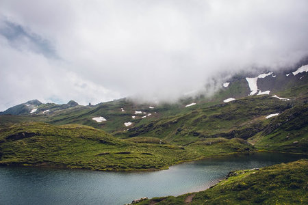 云雾缭绕高山草甸，残雪点缀碧湖静卧绿谷之中