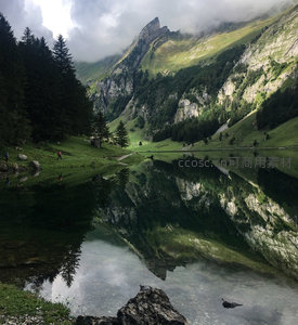 云雾缭绕高山湖泊倒影，徒步者穿行翠绿山谷间