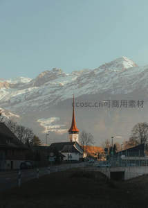 小镇教堂尖顶映雪峰，晨光微照静谧山村街景