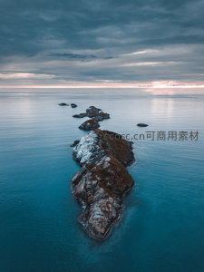 无人机视角下蜿蜒礁石链穿行于平静海面