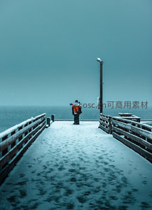 雪覆木栈道上独行者远眺苍茫海面