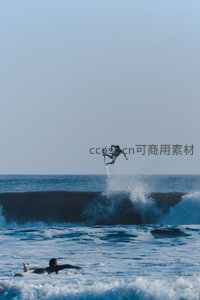 冲浪者腾空跃浪瞬间，湛蓝海面激起白色水花与动感张力