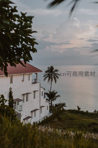白墙红瓦海景别墅，暮色中椰影摇曳静谧时光
