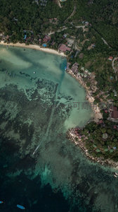 航拍热带岛屿海岸线，珊瑚礁清晰可见，村落依山傍海错落分布