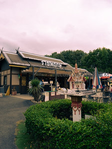 泰式传统小吃店门前：精致佛塔装饰与绿植环绕的市井风情