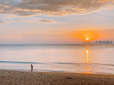 孤影漫步于金色日落海滩，海面波光粼粼倒映绚烂晚霞