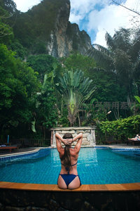 泳池边女子背影望向雨林悬崖，热带度假胜地静谧时光