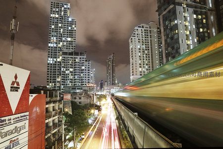 夜幕下疾驰的高架列车与灯火通明的现代都市高楼群
