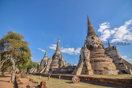 大城府古寺群在蓝天下静默矗立，游客漫步历史遗迹间