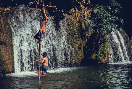 瀑布边孩童攀爬竹竿戏水微距特写