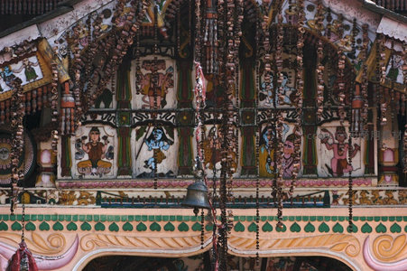 印度寺庙彩绘木雕檐口特写，神像与珠串垂饰细节丰富生动