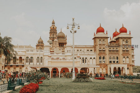 印度迈索尔宫宏伟外观，粉白墙体配红穹顶，游客穿梭花园显皇家气派