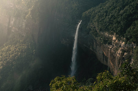 云雾缭绕悬崖间，飞瀑直下绿谷深