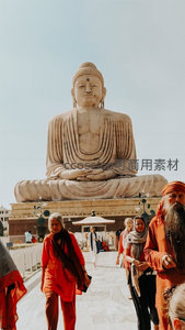 菩提伽耶大佛像前信众朝圣，橙袍僧侣与游客穿行于庄严佛光之下