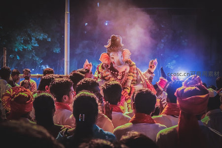 夜色中巨型象神雕像被彩灯与香烟环绕，信众虔诚围观，节日庆典氛围浓烈