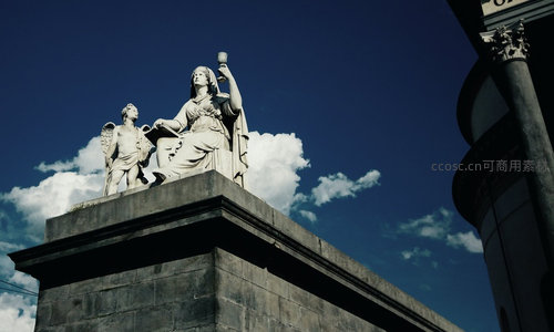 古典女神与天使石雕矗立于蓝天白云下的庄严基座之上