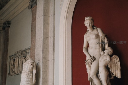 古典雕塑《维纳斯与丘比特》特写，红墙映衬下大理石肌理温润生动