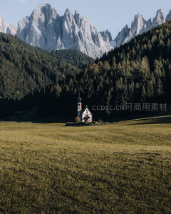 森林环抱山谷中的白色小教堂与锯齿状阿尔卑斯峰