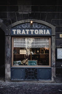 罗马传统 trattoria 餐厅橱窗，复古铁艺门楣与蕾丝窗帘透出地道意式风味