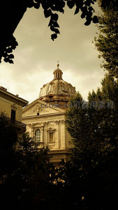 透过树影仰望罗马圣依华堂穹顶，巴洛克建筑在暖调光线下庄严肃穆