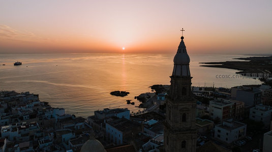 日落时分海滨小镇钟楼剪影，金色海面映照宁静渔港黄昏