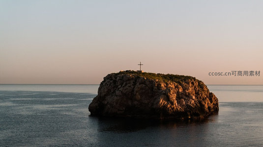 海中孤岩上的十字架在晨曦中静默矗立，映照宁静海面