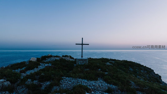 暮色悬崖上的十字架剪影，俯瞰无垠蔚蓝大海与天际线