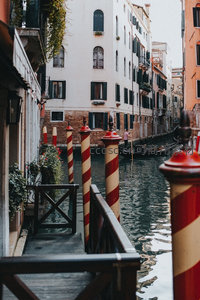 威尼斯水巷窄道实景，红白条纹系船柱与贡多拉静泊水面