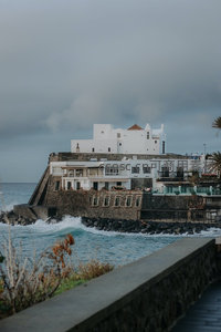 加那利群岛海岸白色建筑群抵御巨浪拍打岩岸