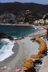 意大利五渔村马纳罗拉海滩航拍，橙色遮阳伞与碧海青山相映成趣