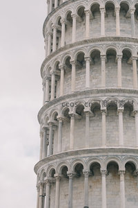 比萨斜塔局部仰拍，罗马式拱廊与石柱细节展现中世纪建筑艺术
