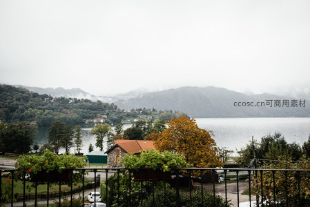 雾霭笼罩湖岸小镇，秋色屋顶与远山云海构成朦胧水墨画