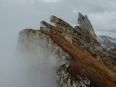 云雾缭绕的 Dolomites 山脊，嶙峋岩峰穿云而出如刀锋刺天