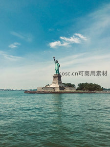 自由女神像矗立自由岛，碧海蓝天映衬铜绿雕像庄严姿态