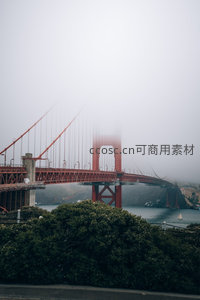 浓雾笼罩的金门大桥若隐若现，红桥身穿云破雾，静谧而神秘